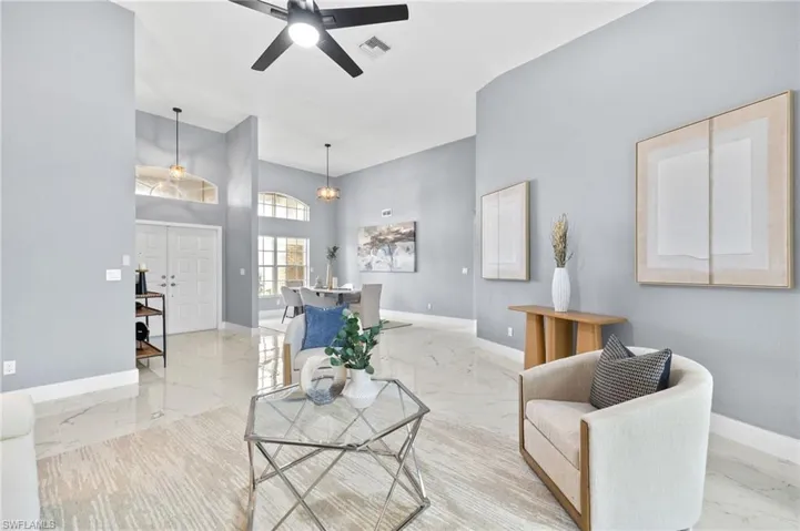 Living area with marble tiled floors, baseboards, a ceiling fan, and a towering ceiling
