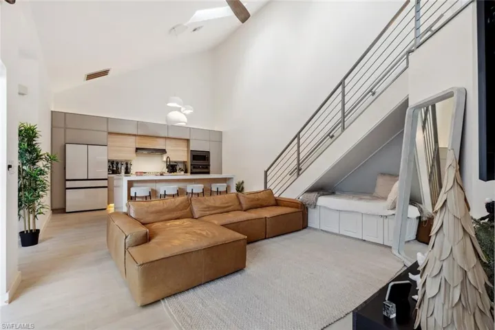 Living room featuring light tile flooring, high vaulted ceiling, and ceiling fan