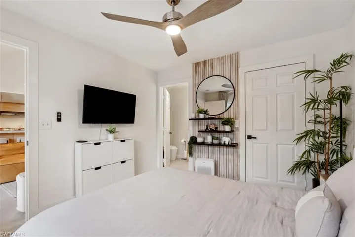 Bedroom featuring ceiling fan, ensuite bathroom, and light tile flooring