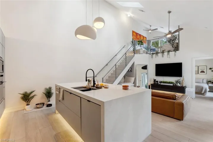 Kitchen featuring high vaulted ceiling, hanging light fixtures, ceiling fan, and light tile flooring