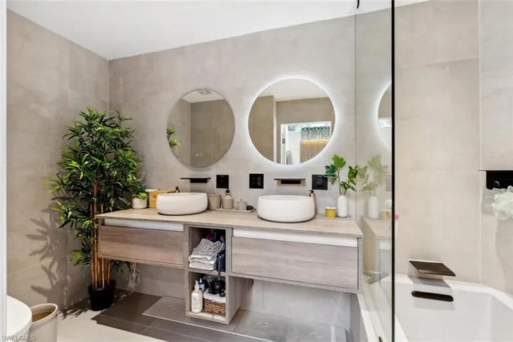 Bathroom with tile walls, tile floors and dual vanity
