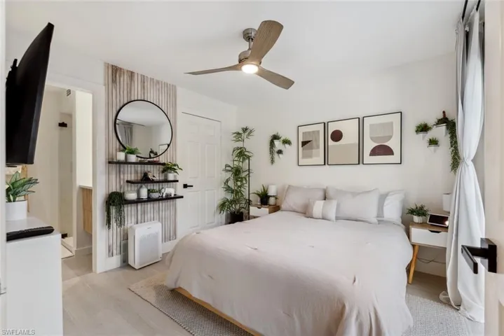 Bedroom featuring ensuite bath, ceiling fan, and light tile flooring