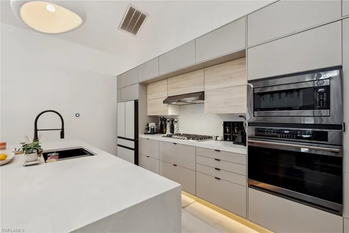 Kitchen with wall exhaust hood, stainless steel appliances, backsplash, and sink