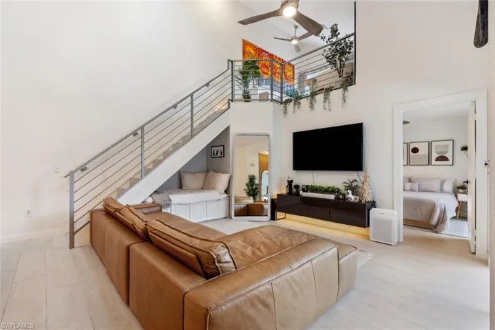 Living room featuring a towering ceiling, light tile floors, and ceiling fan