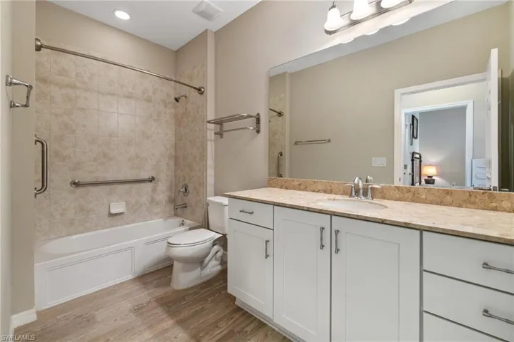Full bathroom featuring toilet, vanity, wood-type flooring, and tiled shower / bath