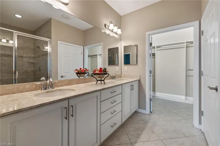 Bathroom featuring a shower with door, vanity, and tile patterned flooring