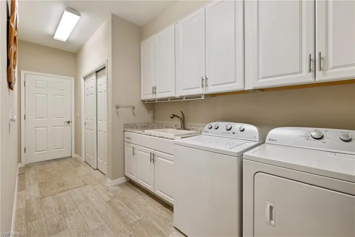 Laundry area featuring light hardwood / wood-style floors, cabinets, independent washer and dryer, and sink