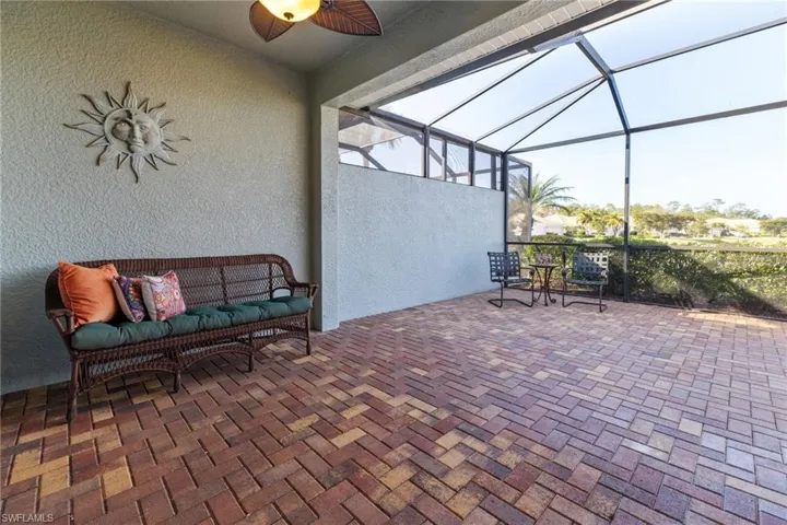 View of patio with an outdoor hangout area, glass enclosure, and ceiling fan
