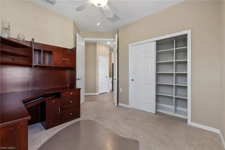 Office area with ceiling fan and light colored carpet