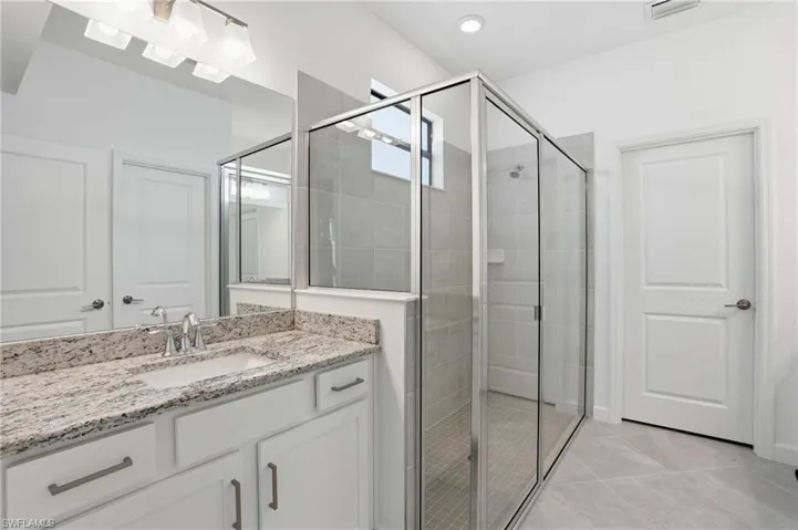 Full bath with a shower stall, vanity, and light tile patterned floors