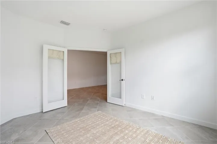 Empty room with french doors and light tile patterned floors