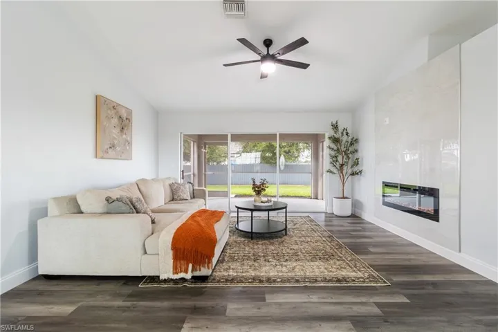 Living area with lofted ceiling, baseboards, visible vents, and ceiling fan