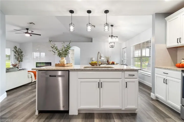 Kitchen with stainless steel dishwasher, dark wood-style floors, a sink, visible vents, and a ceiling fan
