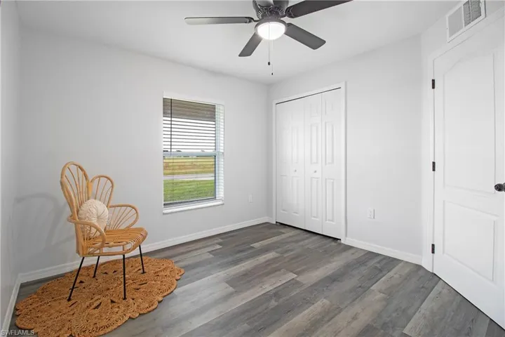 Sitting room with baseboards, visible vents, dark wood-style floors, and ceiling fan