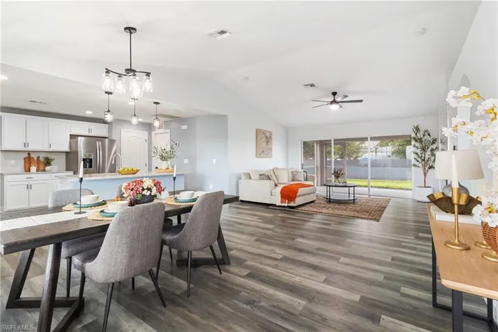 Dining room with lofted ceiling, visible vents, dark wood-style floors, and ceiling fan