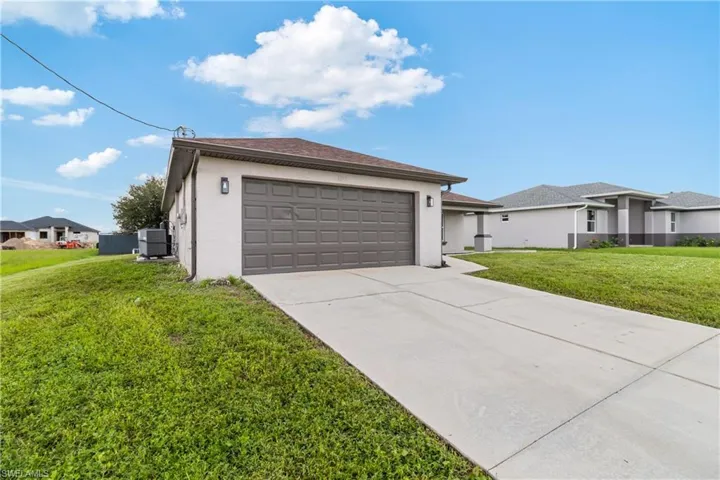 View of front of home featuring a garage, a front lawn, stucco siding, and concrete driveway