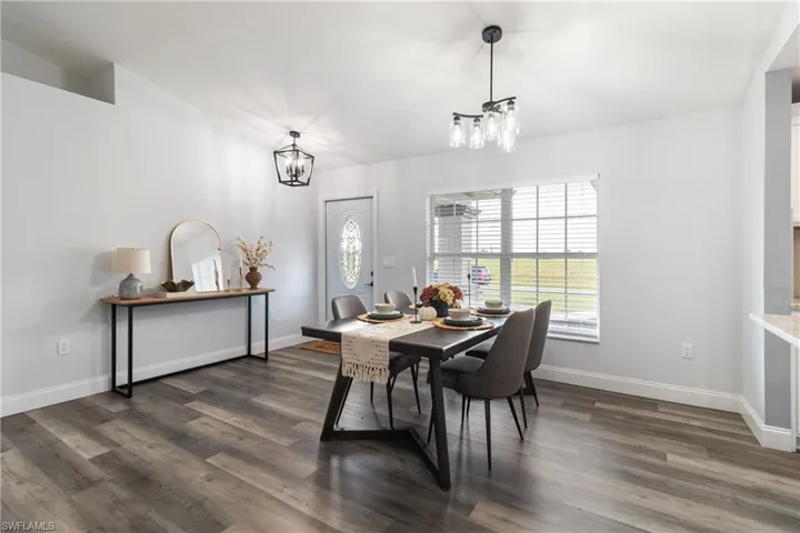 Dining room with a chandelier, baseboards, and dark wood-style floors
