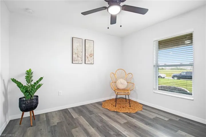 Living area featuring wood finished floors, a ceiling fan, and baseboards