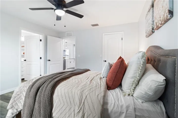Bedroom with baseboards, wood finished floors, visible vents, and a ceiling fan