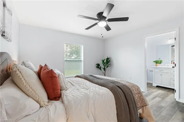 Bedroom featuring a ceiling fan, ensuite bathroom, and light wood finished floors