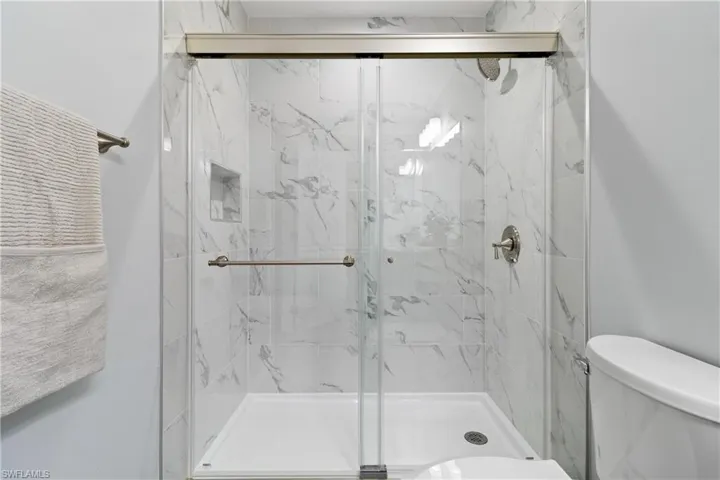 Full bath featuring toilet and a marble finish shower