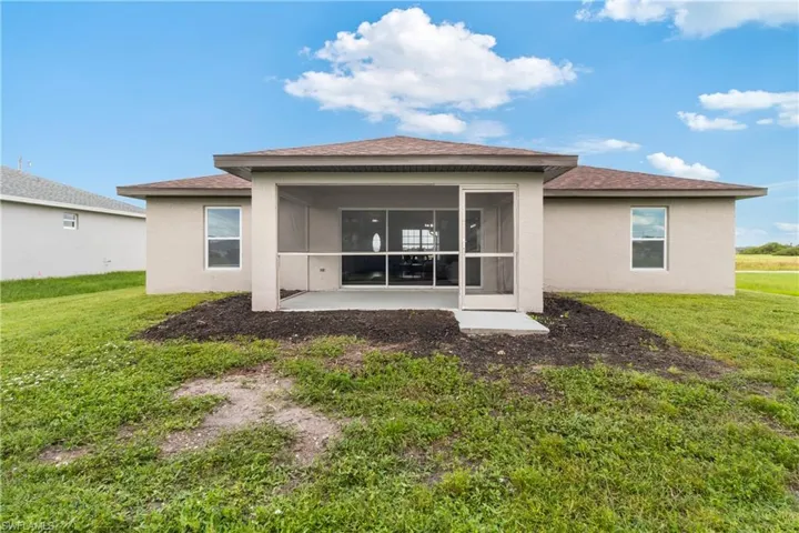 Back of property featuring stucco siding, roof with shingles, a yard, and a patio