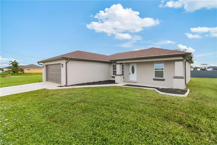 View of front facade with fence, stucco siding, an attached garage, driveway, and a front yard
