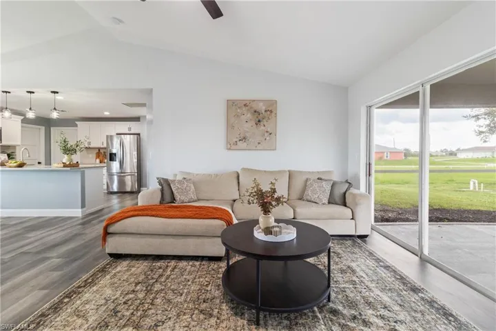 Living area featuring dark wood finished floors, lofted ceiling, and a healthy amount of sunlight