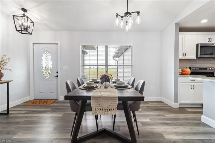 Dining room featuring a chandelier, wood finished floors, baseboards, and recessed lighting