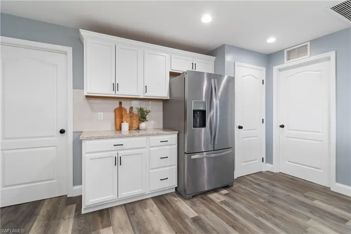 Kitchen featuring visible vents, dark wood-style floors, white cabinetry, and stainless steel fridge with ice dispenser