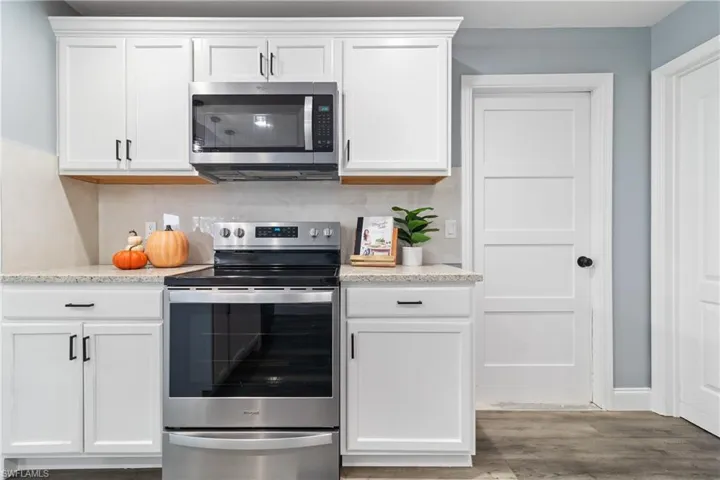 Kitchen with white cabinets, wood finished floors, and stainless steel appliances