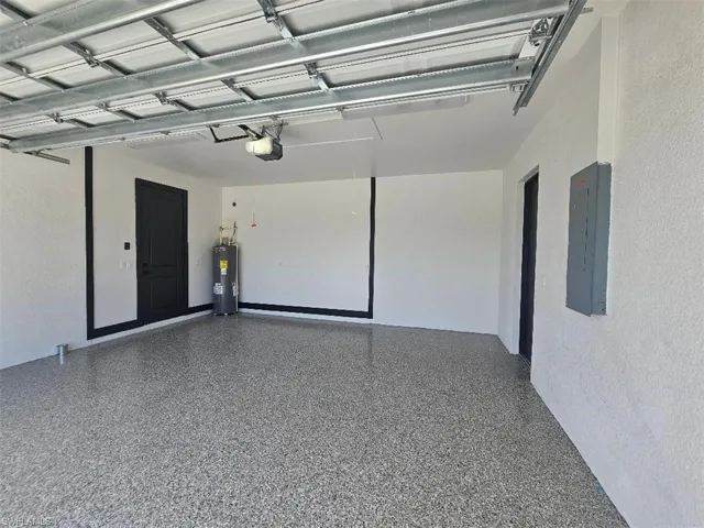 Garage with electric water heater, electric panel, and a garage door opener