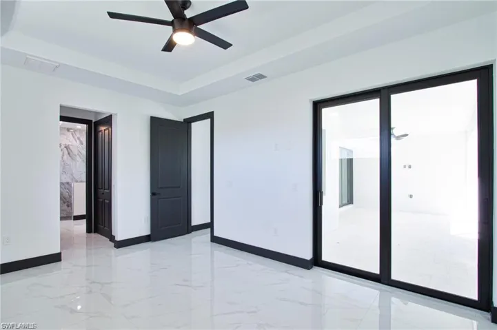 Unfurnished room featuring a tray ceiling, marble finish floor, visible vents, and baseboards