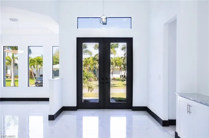 Doorway with marble finish floor, french doors, and baseboards