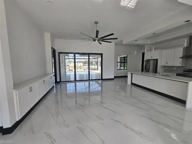 Unfurnished living room featuring marble finish floor, plenty of natural light, and a sink