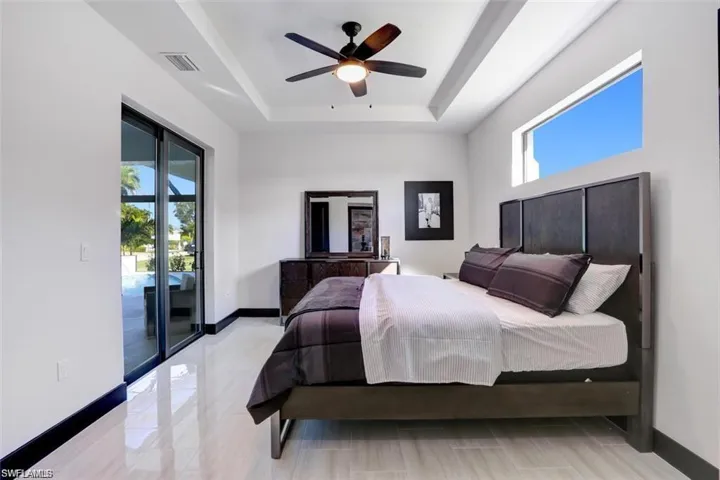 Bedroom with baseboards, visible vents, ceiling fan, access to exterior, and a tray ceiling