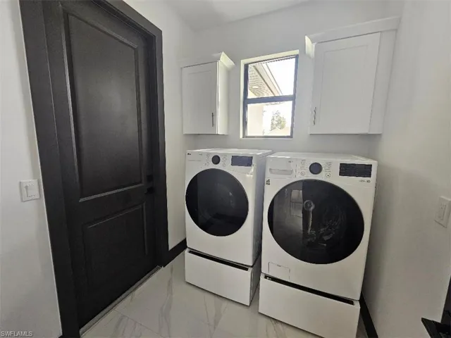 Laundry room featuring marble finish floor, separate washer and dryer, and cabinet space