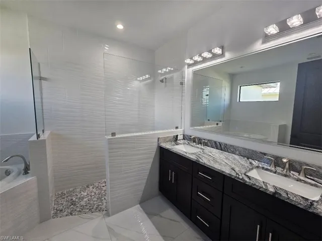 Bathroom featuring marble finish floor, walk in shower, a sink, and a bath
