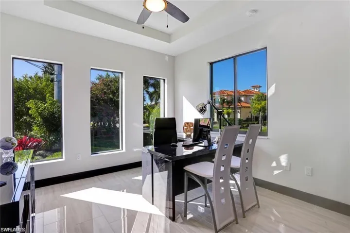Home office featuring ceiling fan, a raised ceiling, and baseboards