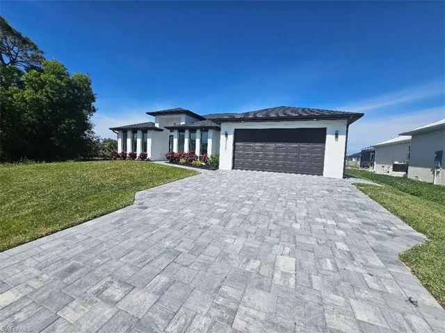 Prairie-style home featuring a garage, a front lawn, decorative driveway, and stucco siding