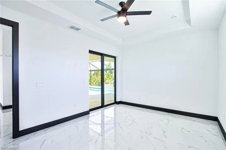 Spare room featuring marble finish floor, visible vents, a tray ceiling, and baseboards