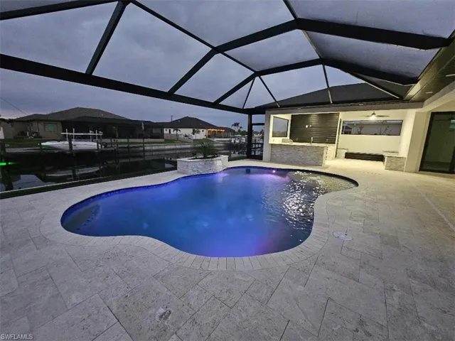 Pool featuring a patio, exterior kitchen, and a lanai