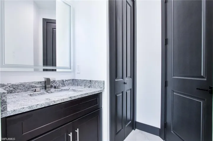 Bathroom with marble finish floor, baseboards, and vanity
