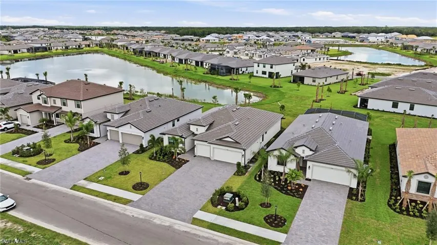 Expansive community featuring multiple residential properties with tiled roofs and paver driveways