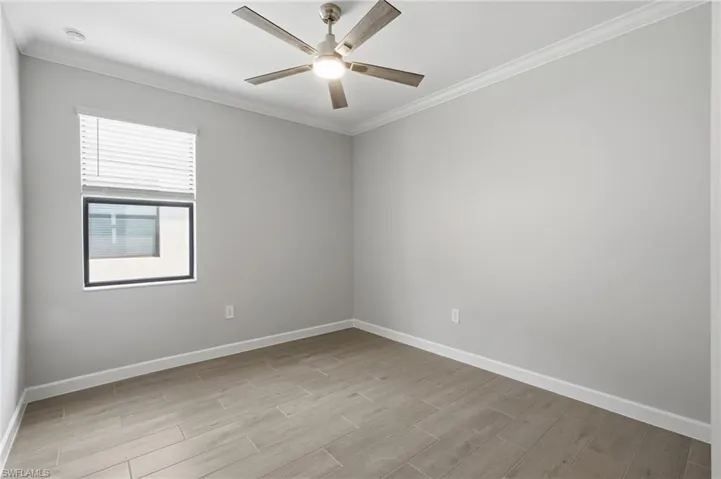 Recessed lighting, crown molding, a ceiling fan with light fixture, wood-look flooring, and a window with blinds