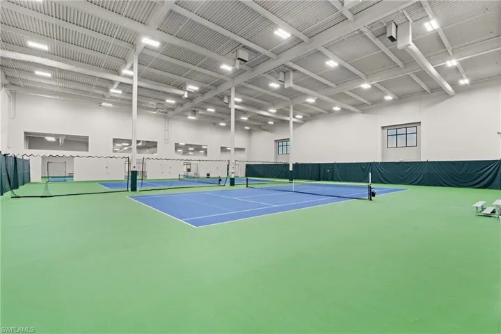 Indoor athletic facility featuring multiple courts, high ceilings with exposed structural elements, and integrated lighting