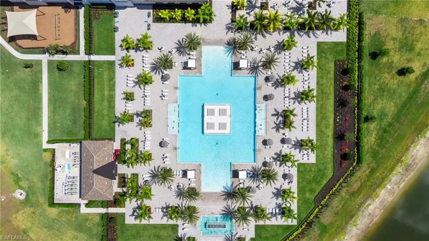 Expansive aquatic recreation area with a large swimming pool, surrounding lounge seating, mature palm trees, and a dedicated playground area