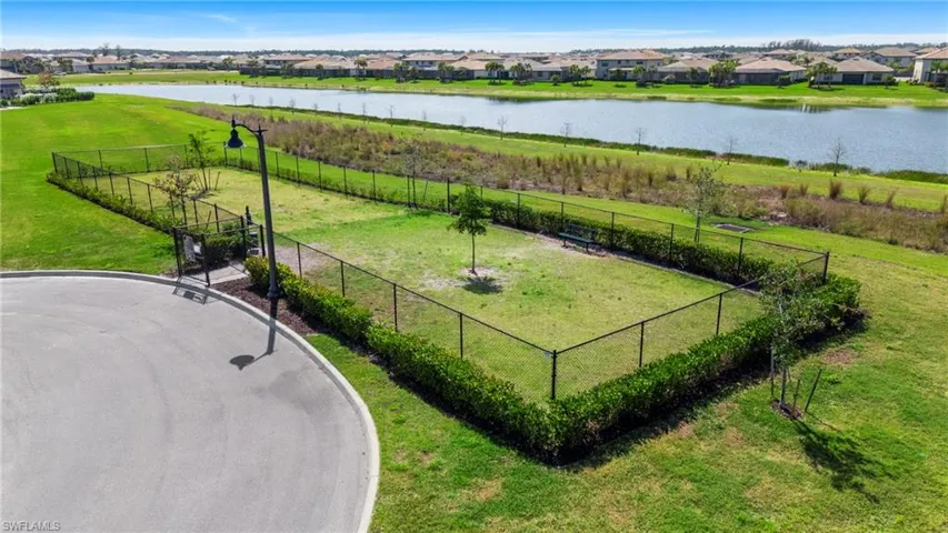 Fenced green space featuring a paved entry, perimeter landscaping, and a street lamp