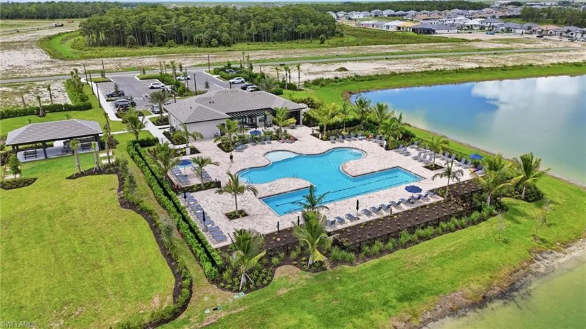 Community clubhouse featuring a freeform swimming pool, extensive pool deck, and shaded outdoor seating areas