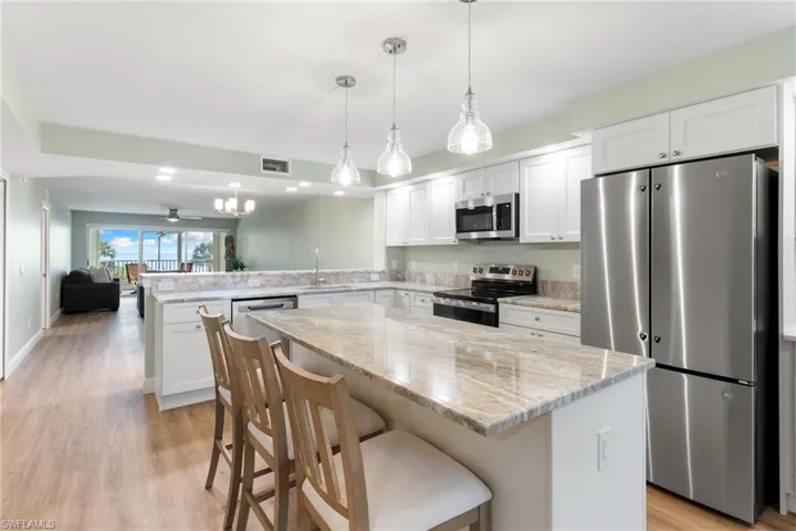 Kitchen featuring stainless steel appliances, open floor plan, a breakfast bar area, white cabinetry, and light wood-style floors
